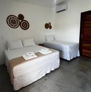 a room with two beds and a wall at Marinho Suítes Milagres in São Miguel dos Milagres