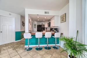 een keuken met een bar met 3 krukken bij St Regis Resort Living- Fitness Center - Sauna - Oceanfront Restaurant on Site in Chadwick Acres