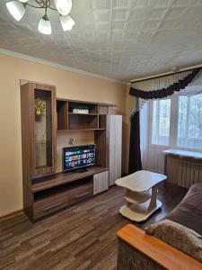 a living room with a couch and a tv at Lux Apartment on Potanina 19 in Ustʼ-Kamenogorsk