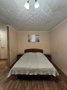 a bedroom with a bed with a white comforter at Lux Apartment on Potanina 19 in Ustʼ-Kamenogorsk