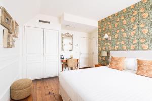 a bedroom with a white bed and a floral accent wall at Hotel Edouard VII in Biarritz
