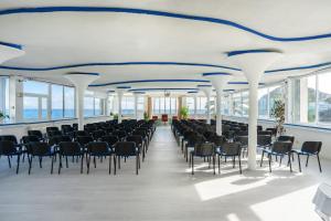 a large room with chairs and tables and windows at Miramare Sea Resort & Spa in Ischia