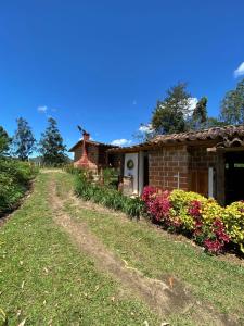 ein Backsteinhaus mit Blumen an einer unbefestigten Straße in der Unterkunft Hotel Campestre - CIUDADELA EL ARTESANO in Carolina del Principe + 27 Fotos
