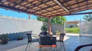 a patio with a table and chairs under a pergola at Casa proxima Praia com Piscina Incrivel em Rio das Ostras in Casimiro de Abreu
