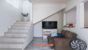a living room with a staircase with a couch and a television at Casa proxima Praia com Piscina Incrivel em Rio das Ostras in Casimiro de Abreu +16 photos