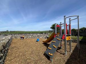 a playground with a slide and a slideintend at Ystumgwern Luxury Barn Conversions in Dyffryn