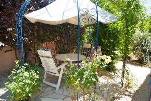 a table and chairs under an umbrella in a garden at B&B Villa Viva Vitale in Pierrevert