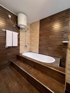 a bath tub in a bathroom with wooden walls at Grand Orchid Hotel Apartment in Duqm