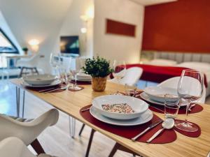 a wooden table with plates and wine glasses on it at Besilima Apartments Deidesheim - zentral & ruhig am Kurpark in Deidesheim +193 photos