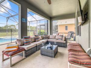 ein Wohnzimmer mit Sofa, Stühlen und Fenstern in der Unterkunft 7BR Villa in Emerald Island w/ Resort Perks in Kissimmee