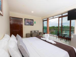 a bedroom with a large white bed with a large window at Hotel San Marino Tarapoto in Tarapoto
