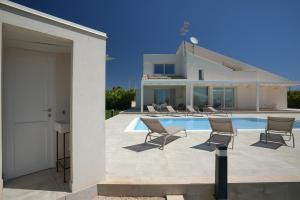 a house with a swimming pool and chairs on a patio at Villa Aria - Modica in Modica