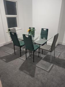 a glass table with four chairs and a vase at Seaside 3 Bedroom Home in Ramsgate +8 photos
