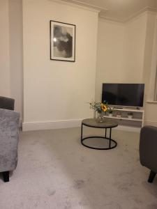 a living room with a table and a flat screen tv at Seaside 3 Bedroom Home in Ramsgate