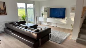 a living room with a black leather couch and a television at Ostalb Inn - Haus Emely in Schwäbisch Gmünd