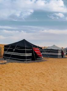 un gruppo di tende che si trovano sulla sabbia di Authentic Nomads camp ad Al Wāşil