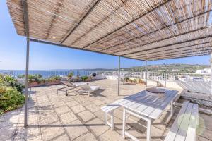Un patio con mesa y sillas y el mar. en Villa Blu la Panoramica, en Castro di Lecce