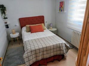 una piccola camera con letto con testiera rossa di Casa Flor Delfin Ribadeo a Ribadeo