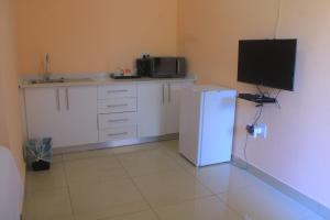 a kitchen with a refrigerator and a tv on the wall at Mco residence self catering accommodation in Lusikisiki