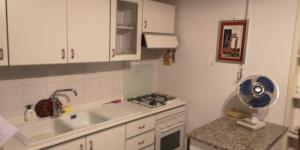 Una pequeña cocina con gabinetes blancos y un fregadero. en LOCRI SUITE più CAMERE, en Locri 67 fotos más