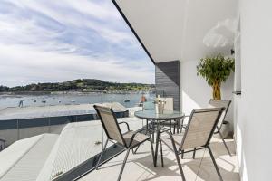 a balcony with a table and chairs and a view of the water at Teign View, Grand Banks in Teignmouth