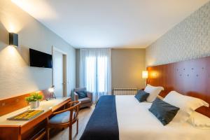 ビックにあるHotel J. Balmes Vicの大きなベッドと机があるホテルの部屋