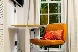 una silla naranja con una almohada frente a una ventana en Families and large groups, with TVs in every room, en Palm Bay