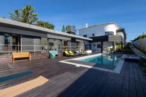 a house with a wooden deck with a swimming pool at Villa Lapax by Ericeira Property in Ericeira
