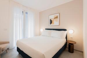 a white bedroom with a bed and a chair at RELSTAY - De Angeli in Milan
