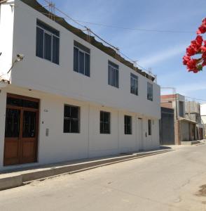 un edificio blanco con una puerta marrón en una calle en Hospedaje el Telar, en Nazca