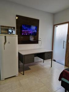 a desk with a refrigerator and a tv on the wall at Apartamento Studio in Diamantina