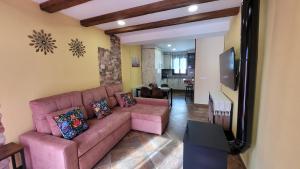 a living room with a pink couch and a tv at Alojamiento rural Casa Clara la Pescaora in Trevélez