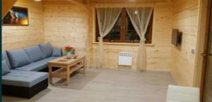 a living room with a blue couch and a table at Domek AGA in Kruklanki