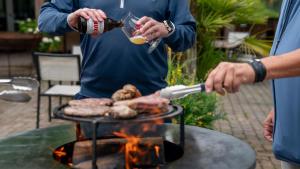 a man is cooking meat on a grill at Hotel Martensplek in Tiendeveen