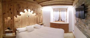 a bedroom with a white bed and a wooden wall at Daniela Apartment in Cortina dʼAmpezzo
