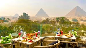 una tavola con sopra del cibo con le piramidi sullo sfondo di NEMES Pyramids View INN a Il Cairo