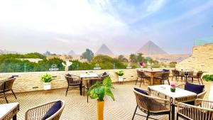 un patio con tavoli e sedie con piramidi sullo sfondo di NEMES Pyramids View INN a Il Cairo