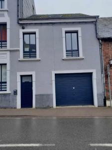 two blue garage doors on a white building at Maison d'hôtes au coeur de la Gaume in Virton