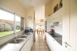 a kitchen with two sinks and a large window at Villa 145 m near ocean with pool and garden in Moliets-et-Maa