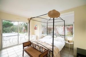 a bedroom with a four poster bed and a balcony at Villa 145 m near ocean with pool and garden in Moliets-et-Maa +23 photos