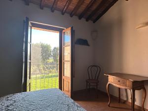 Un dormitorio con una cama y un escritorio y una ventana. en Fornace del Conte, en Abbadia di Montepulciano