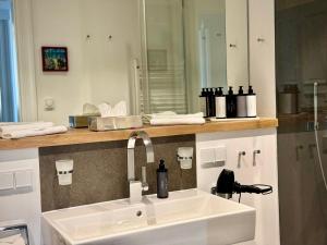 ein Badezimmer mit Waschbecken und Spiegel in der Unterkunft FIRST im FIRST Sellin, Penthouse Meer & Meer mit phänomenalem Ostseeblick in Ostseebad Sellin