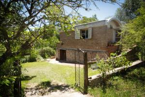 a brick house with a gate in a yard at Alquilo Monoambiente por día in Cuesta Blanca