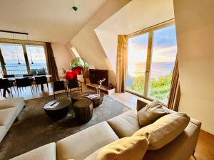 ein Wohnzimmer mit einer Couch und einem Tisch in der Unterkunft FIRST im FIRST Sellin, Penthouse Meer & Meer mit phänomenalem Ostseeblick in Ostseebad Sellin