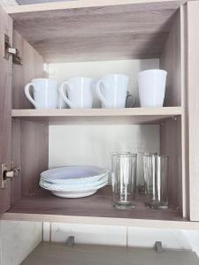 a shelf with cups and plates and glasses on it at Pousada Brisa do Mar in Tramandaí