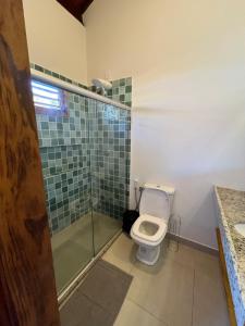 a bathroom with a toilet and a glass shower at Casa Umbuê 01 - Vista Mar in Cayru
