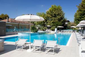 a pool with white chairs and umbrellas next to it at Suite Apartments Prestige in Bellaria-Igea Marina +136 photos