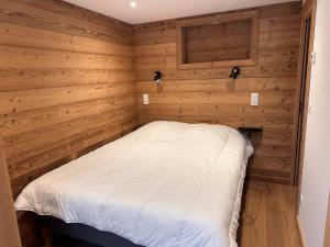 - une petite chambre avec des murs en bois et un lit blanc dans l'établissement Appartement cozy 3P à 5m du front de neige avec parking et terrasse - FR-1-464-236, à Pralognan-la-Vanoise
