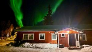 a cabin with the aurora in the sky behind it at Soukolo Apartments in Äkäslompolo