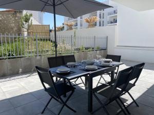 einem schwarzen Tisch mit Stühlen und einem Sonnenschirm auf einer Terrasse in der Unterkunft Royan T3 Moderne - Bord De Mer - 6 Pers, Parking, Terrasse - FR-1-738-35 in Royan